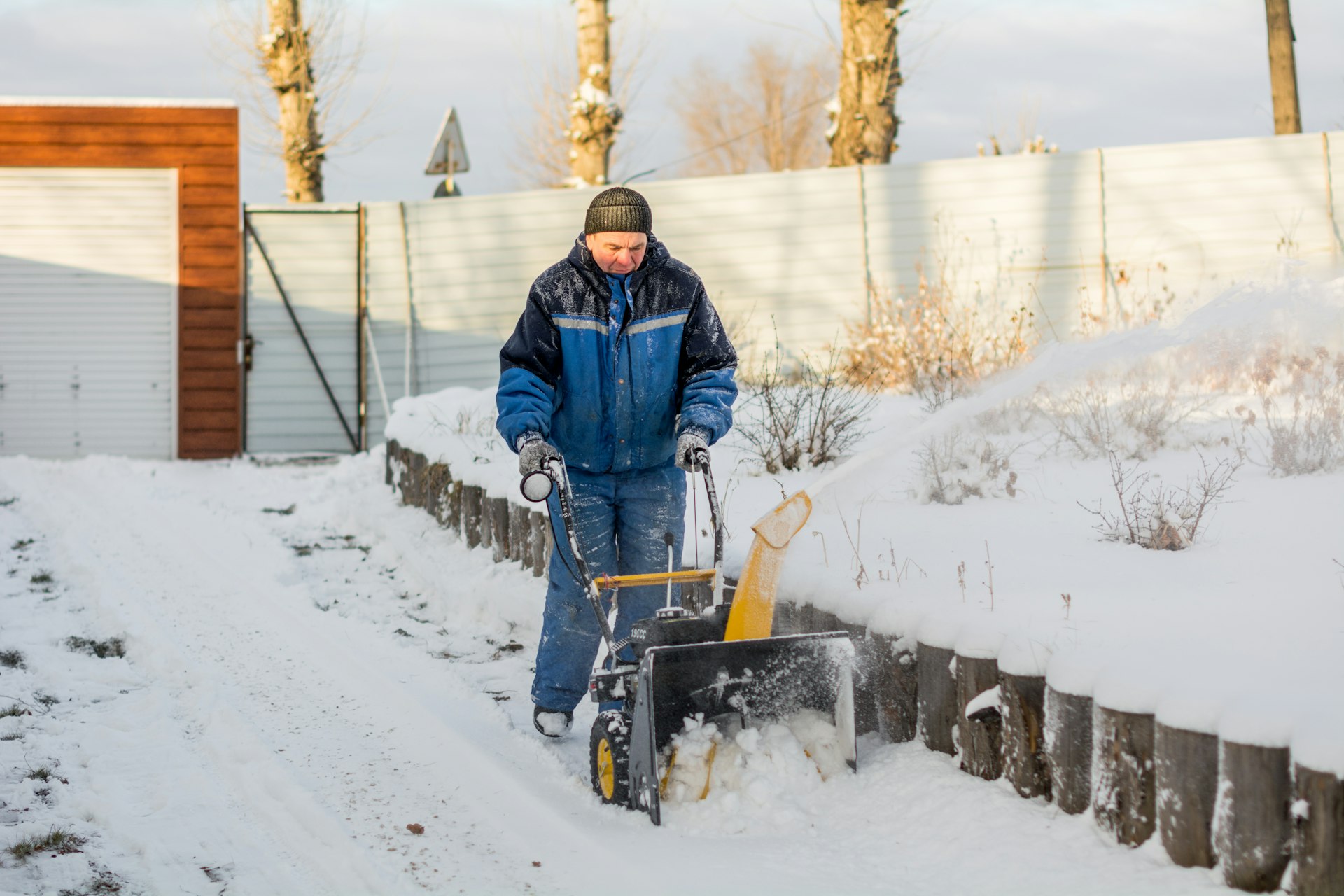 Snøfreser i arbeid på en snødekt innkjørsel en vinterdag